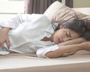 Woman laying down, holding abdomen in pain