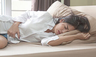 Woman laying down, holding abdomen in pain